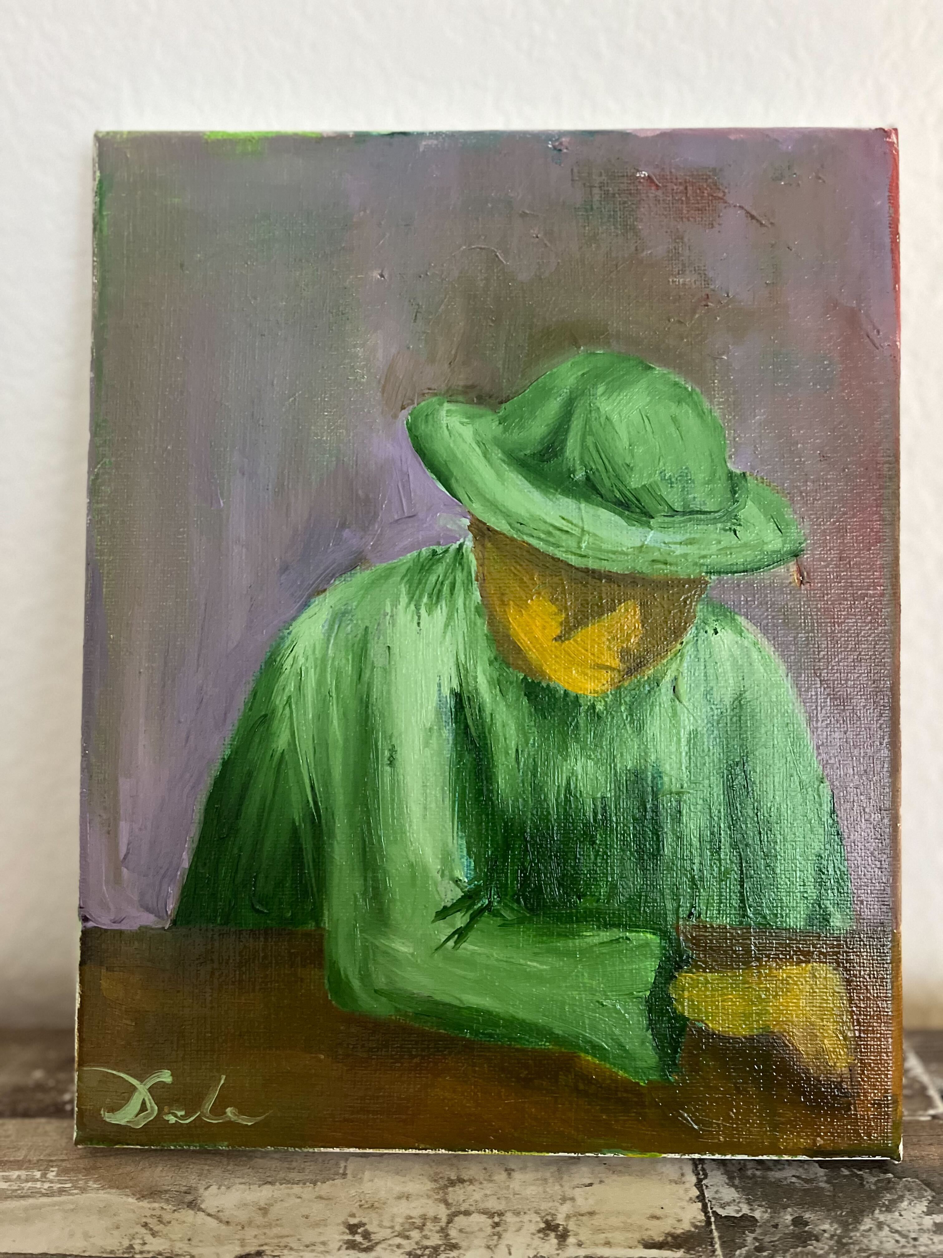 Person in green hat and cloak sitting in front of a table